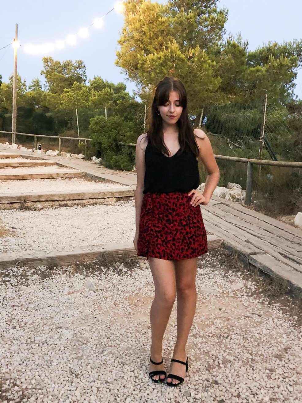 Besma wears a black top with red leopard-print skirt