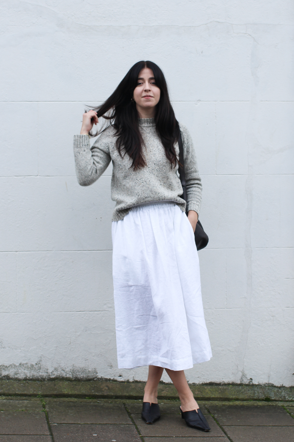 Besma wears speckled jumper with white linen skirt
