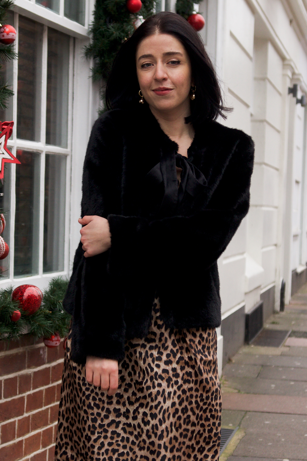 Besma smiles wearing faux fur coat and leopard print dress outfit