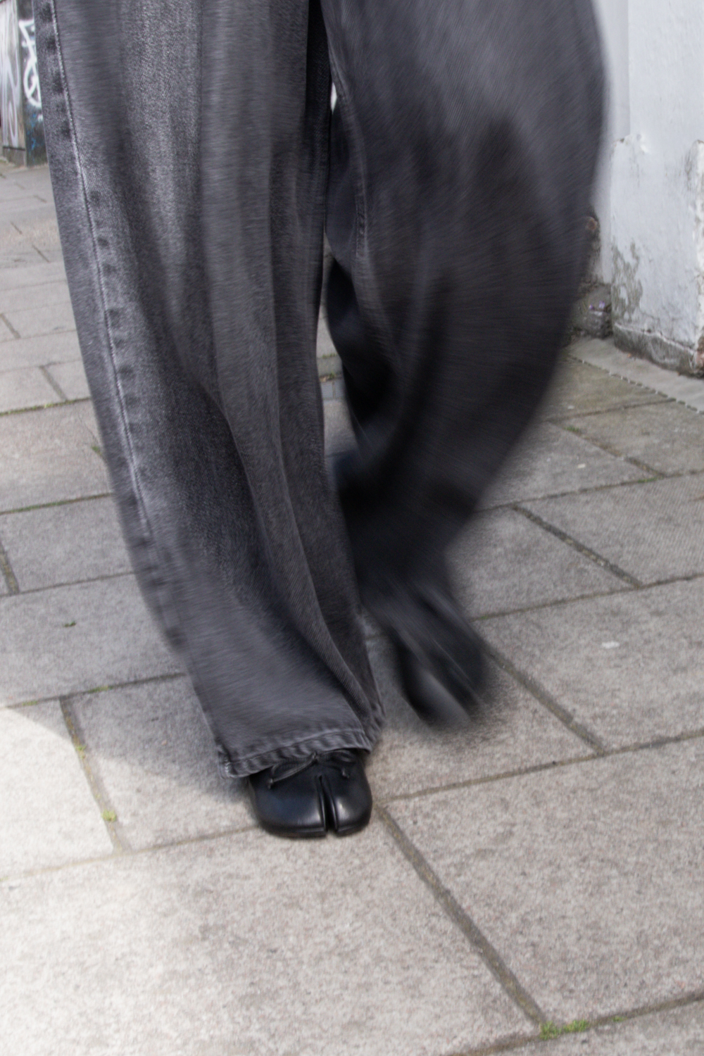 Women walking in black tabi shoes worn with grey jeans