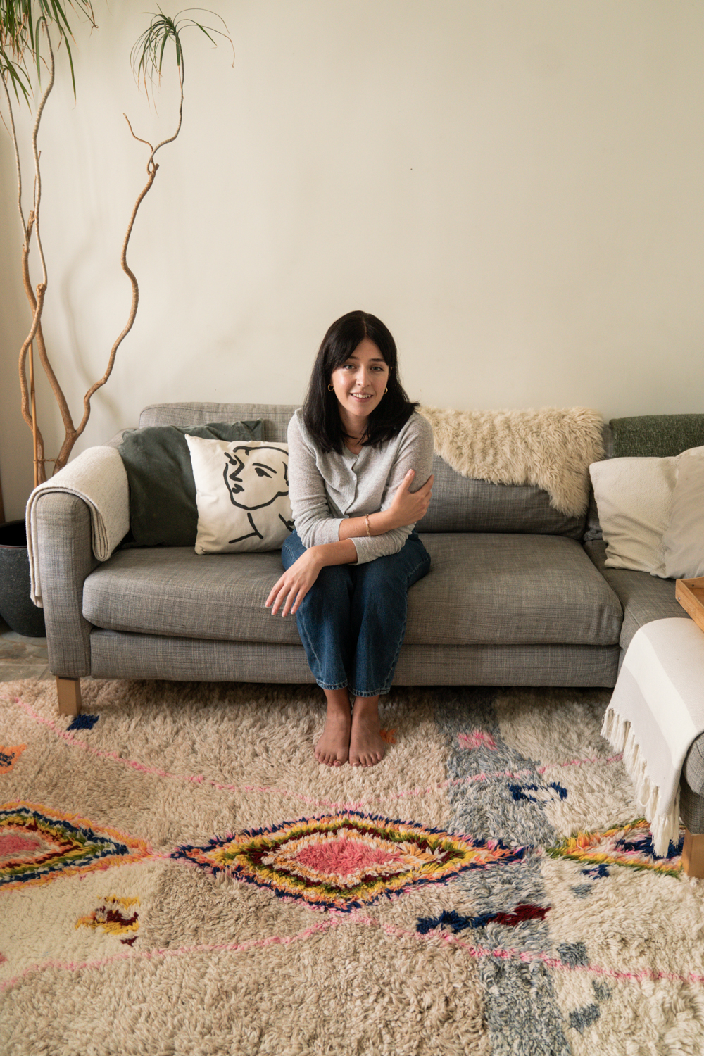 Besma sat on sofa with rug